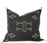 Black Moroccan pillow with intricate red and white patterns on a white background